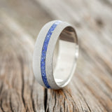 Shown here is "Vertigo", a handcrafted men's wedding ring featuring a lapis lazuli inlay with a sandblasted finish, upright facing left.