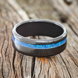 Shown here is "Vertigo", a custom, handcrafted men's wedding ring featuring a blue opal inlay, laying flat. Additional inlay options are available upon request.