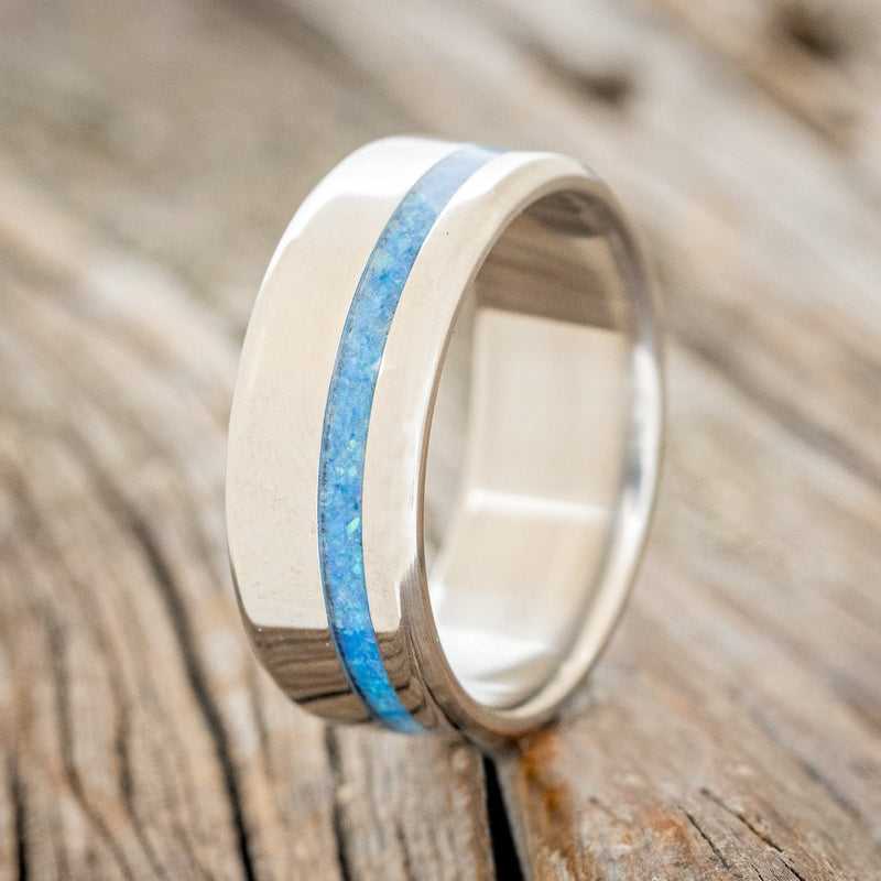 Shown here is "Vertigo", a custom, handcrafted men's wedding ring featuring a blue opal inlay, upright facing left. Additional inlay options are available upon request.