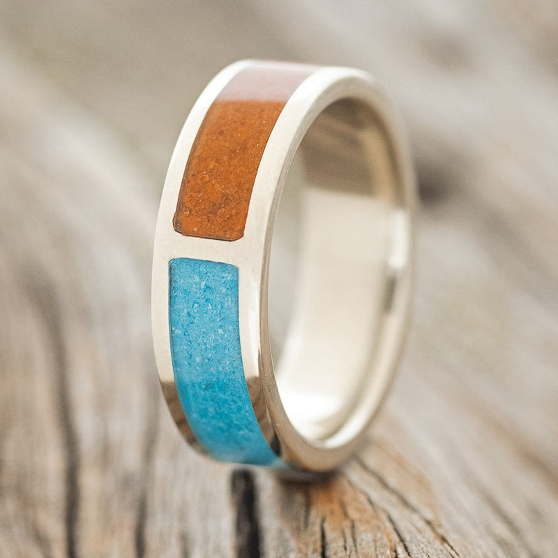 Shown here is "Janus", a custom, handcrafted split men's wedding ring featuring a terracotta & turquoise inlays, upright facing left. Additional inlay options are available upon request.
