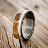 Shown here is "Raptor", a custom, handcrafted men's wedding ring featuring an authentic whiskey barrel stave and elk antler, upright facing left. Additional inlay options are available upon request.