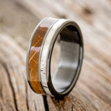 Shown here is "Raptor", a custom, handcrafted men's wedding ring featuring authentic whiskey barrel oak and elk antler on a fire-treated black zirconium band, upright facing left. Additional inlay options are available upon request.