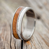 Shown here is "Raptor", a custom, handcrafted men's wedding ring featuring an authentic whiskey barrel stave and elk antler, upright facing left. Additional inlay options are available upon request.