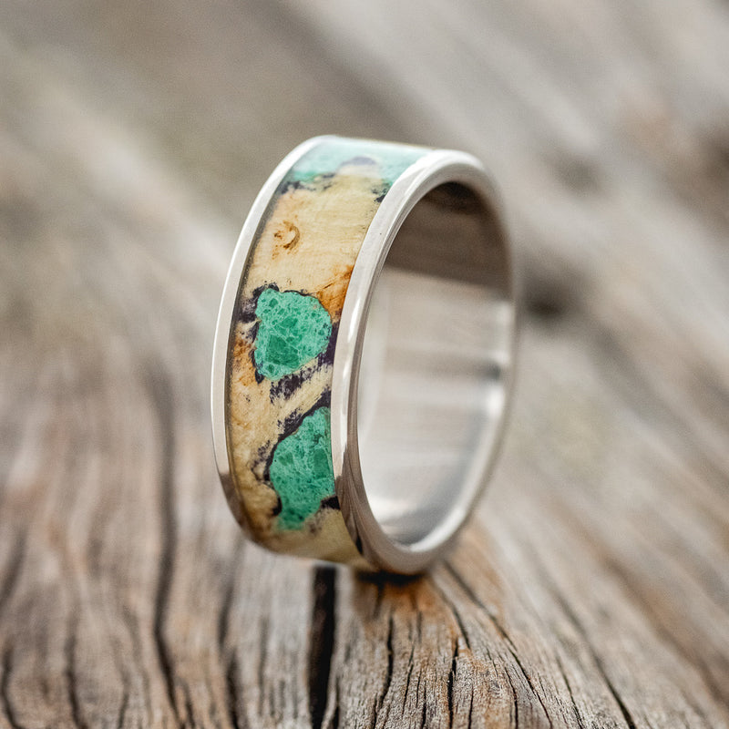 Shown here is "Rainier", a handcrafted men's wedding ring featuring buckeye burl wood with malachite inlays set into the burls, upright facing left.