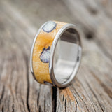 Shown here is "Rainier", a handcrafted men's wedding ring featuring buckeye burl wood with fire & ice opal inlays set into the burls, upright facing left.