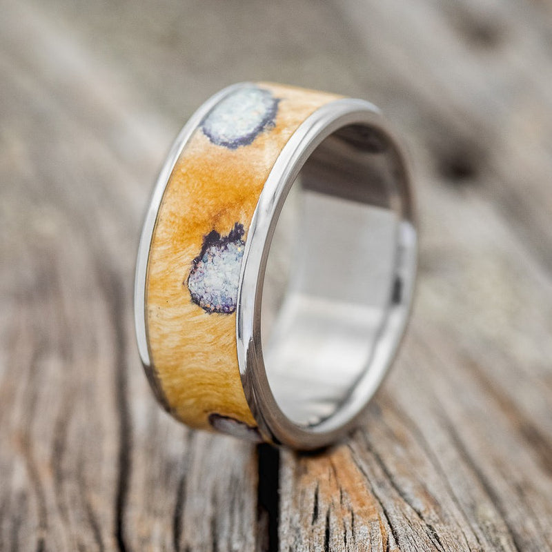Shown here is "Rainier", a handcrafted men's wedding ring featuring buckeye burl wood with fire & ice opal inlays set into the burls, shown here on a titanium band, upright facing left. Additional inlay options are available upon request.