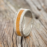 Shown here is "Rainier", a custom, handcrafted men's wedding ring featuring a whiskey barrel and antler inlay, upright facing left. 