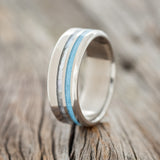 Shown here is "Cosmo", a custom, handcrafted men's wedding ring featuring turquoise and mother of pearl inlays, upright facing left.