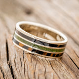 Shown here is "Rio", a custom, handcrafted men's wedding ring featuring 3 channels with white and black ebony wood and moss inlays on a 14K white gold band, facing right. Additional inlay options are available upon request.