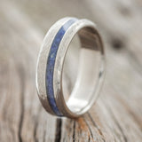 Shown here is "Vertigo", a custom, handcrafted men's wedding ring featuring an offset lapis lazuli inlay with a hammered finish, upright facing left. Additional inlay options are available upon request.