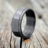 Shown here is "Sedona", a handcrafted men's wedding ring featuring a fire-treated solid black zirconium band with hammered edges, upright facing left. 