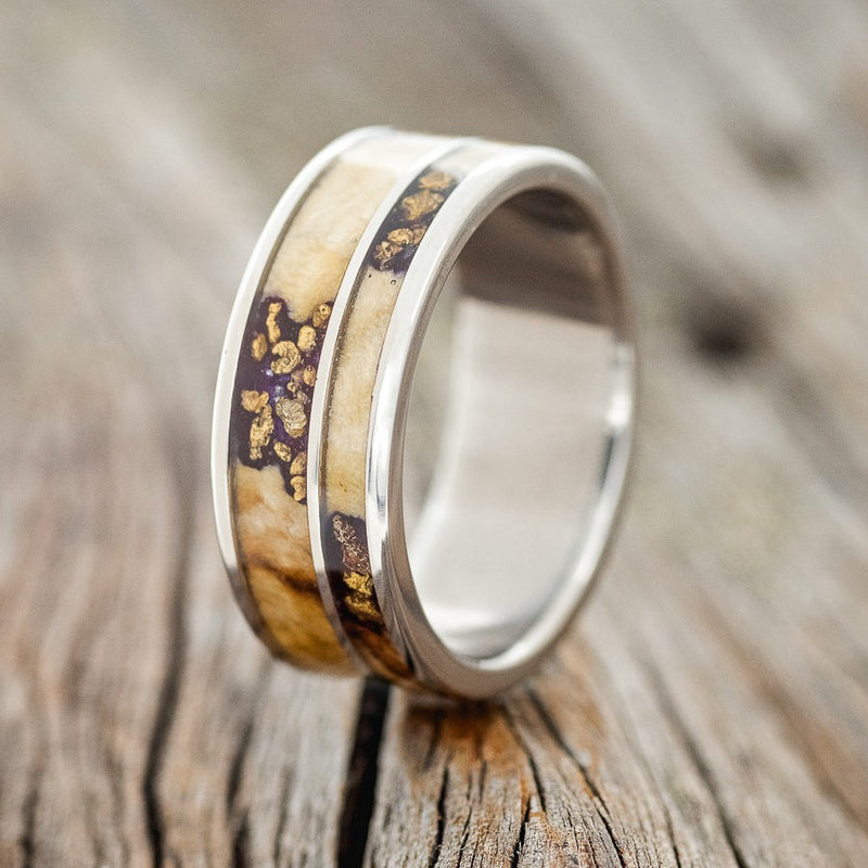 Shown here is "Raptor", a custom, handcrafted men's wedding ring featuring 2 channel inlays with buckeye burl wood and gold nugget set into burls, shown here on a titanium band, upright facing left. Additional inlay options are available upon request.