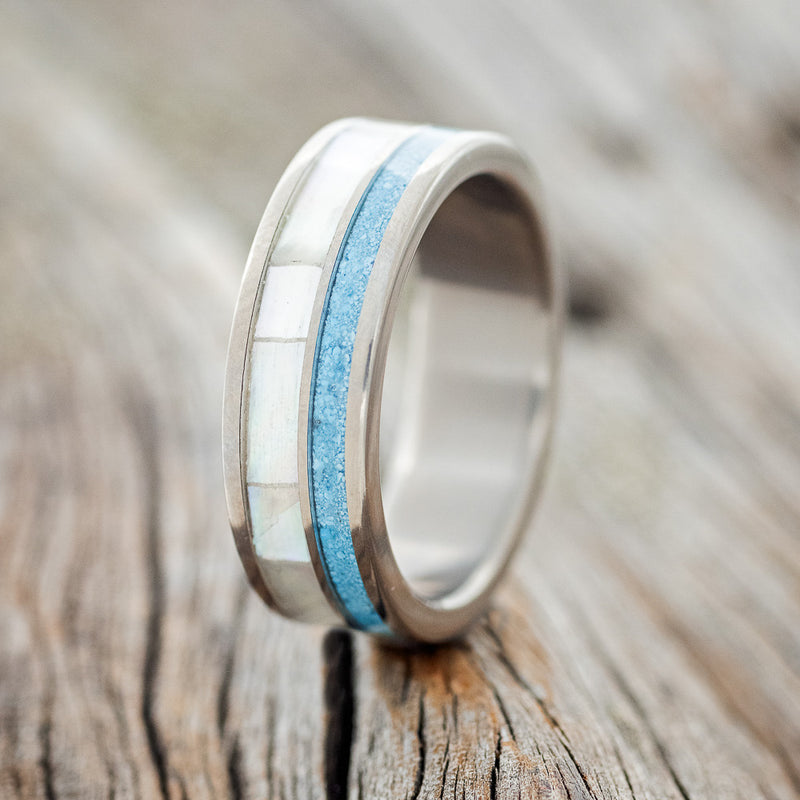 Shown here is "Raptor", a custom, handcrafted men's wedding ring featuring mother of pearl and turquoise inlays, upright facing left. 
