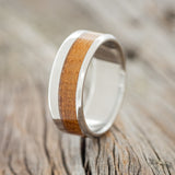 Shown here is "Tanner", a custom, handcrafted men's wedding ring featuring a whiskey barrel inlay, upright facing left.