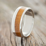 Shown here is "Tanner", a custom, handcrafted men's wedding ring featuring a whiskey barrel inlay, upright facing left. Additional inlay options are available upon request.