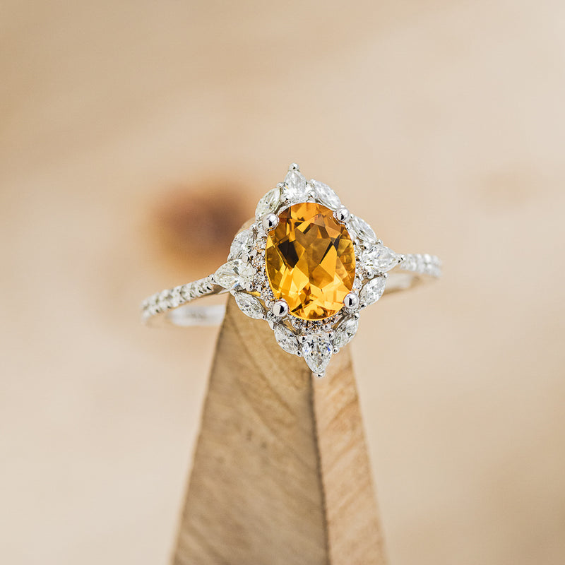 Shown here is "North Star", an oval citrine women's engagement ring with a diamond halo and diamond accents, on stand facing slightly right. Many other center stone options are available upon request.
