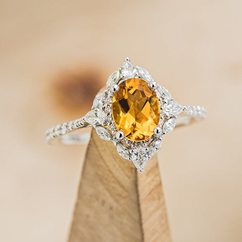 Shown here is "North Star", an oval citrine women's engagement ring with a diamond halo and diamond accents, on stand facing slightly right. Many other center stone options are available upon request.