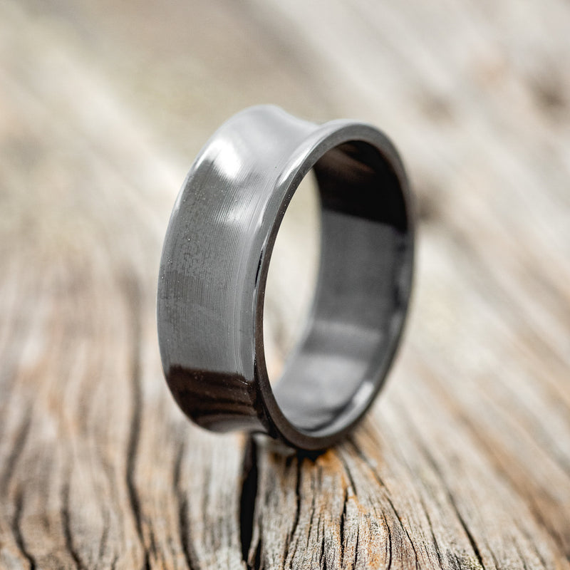 Shown here is a handcrafted men's wedding ring featuring a concave band, upright facing left. 