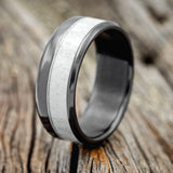 Shown here is "Tanner", a custom, handcrafted men's wedding ring featuring an antler overlay, shown here on a fire-treated black zirconium band, upright facing left. Additional inlay options are available upon request.
