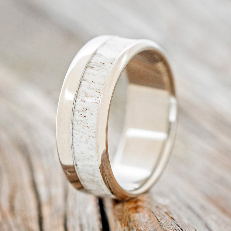 Shown here is "Tanner", a custom, handcrafted men's wedding ring featuring a naturally shed elk antler inlay, upright facing left. Additional inlay options are available upon request.