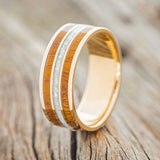 Shown here is "Rio", a custom, handcrafted men's wedding ring featuring 3 channels with diamond dust and ironwood inlays on a 14K gold band, upright facing left. Additional inlay options are available upon request.
