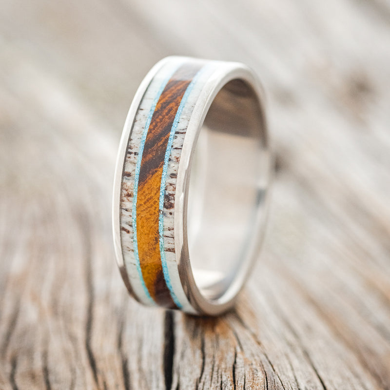 Shown here is "Rainier", a custom, handcrafted men's wedding ring featuring a single channel inlay with antler, turquoise, and ironwood, upright facing left.
