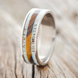 Shown here is "Rainier", a custom, handcrafted men's wedding ring featuring a single channel inlay with antler, turquoise, and ironwood on a titanium band, upright facing left. Additional inlay options are available upon request.