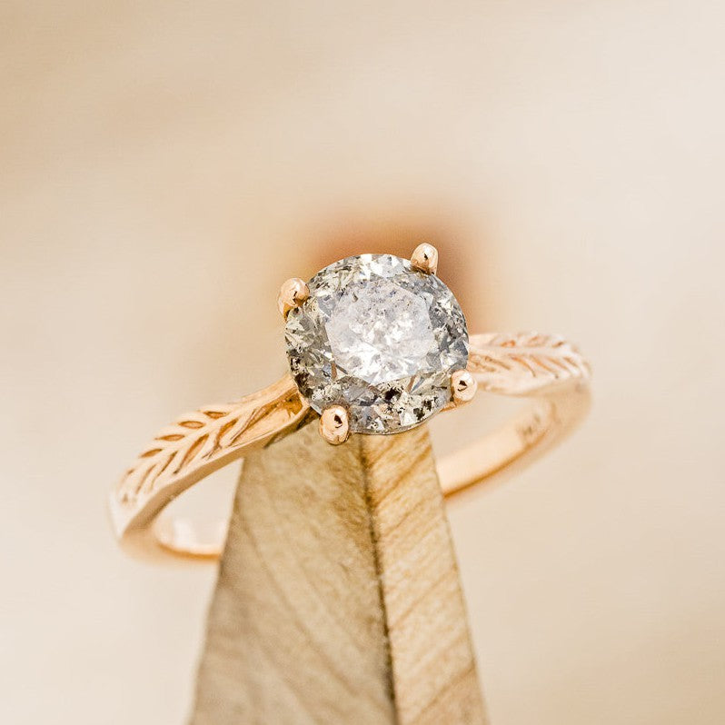 Shown here is "Hope", a round solitaire-style salt and pepper diamond women's engagement ring with feather accents, on stand facing slightly right. Many other center stone options are available upon request.