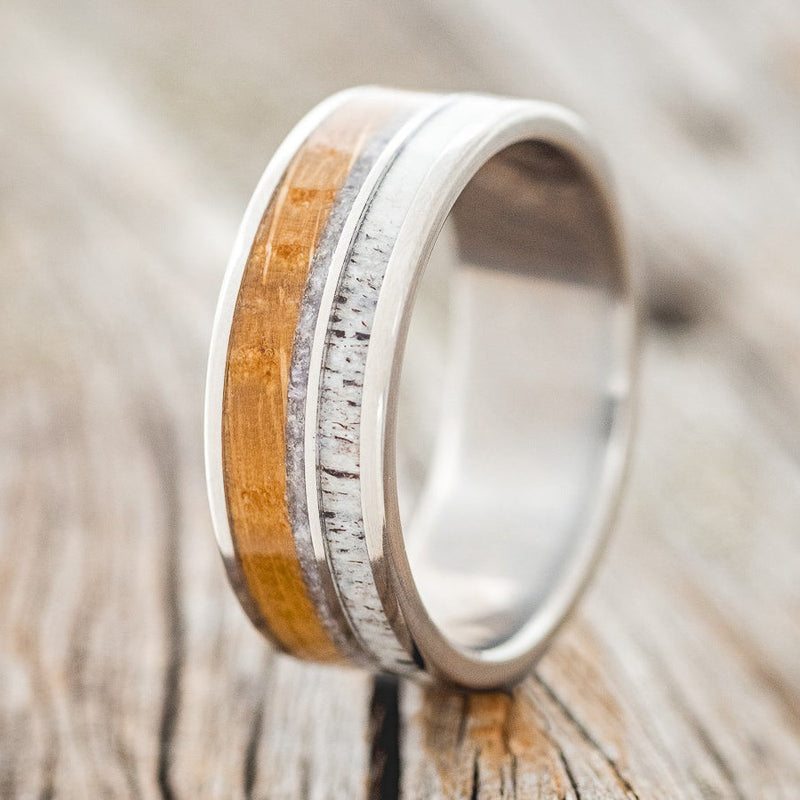 Shown here is "Element", a custom, handcrafted men's wedding ring featuring 2 channels with elk antler, charoite, and whiskey barrel oak inlays, upright facing left. Additional inlay options are available upon request.