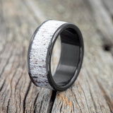 Shown here is "Rainier", a custom, handcrafted men's wedding ring featuring antler inlay and shown here on a fire-treated black zirconium band, upright facing left. Additional inlay options are available upon request.