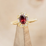 Shown here is "Cleopatra", an art deco-style oval garnet women's engagement ring with diamond accents, on stand front facing. Many other center stone options are available upon request.