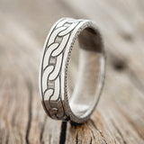 Shown here is "Link", a custom, handcrafted men's wedding ring featuring a chain engraving on a titanium band. It can be customized to feature just about any engraving design you can dream up, upright facing left.