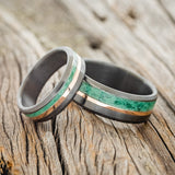 Shown here is a matching wedding band set featuring two "Tanner" rings with malachite and 14K rose gold inlays, shown here on brushed, fire-treated black zirconium bands, laying together.