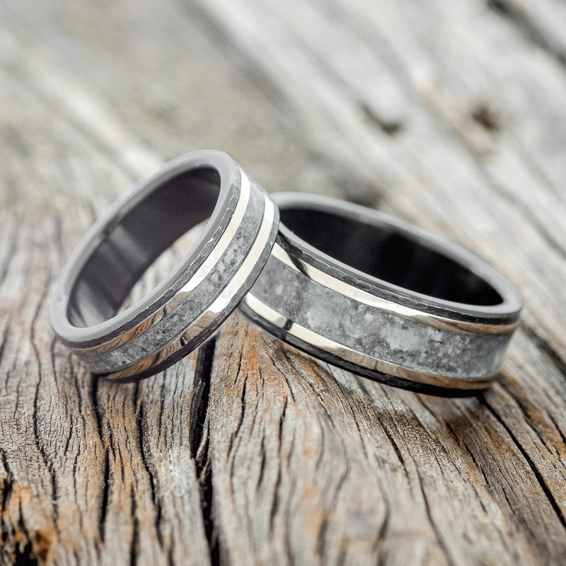 Shown here is "Hollis", a matching wedding band set featuring two rings with crushed moonstone and 2 14K white gold inlays, shown here on a hammered, fire-treated black zirconium bands, laying together.