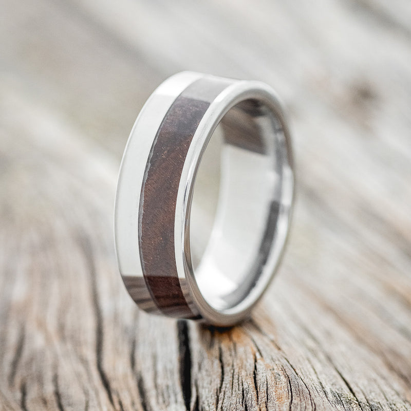 Shown here is "Tanner", a custom, handcrafted men's wedding ring featuring a walnut wood inlay, upright facing left.