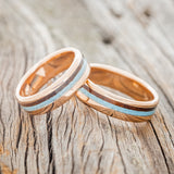 Shown here is a matching wedding band set featuring two "Castor" rings with ironwood and turquoise inlays, shown here on 14K gold bands, laying together. Additional inlay options are available upon request.