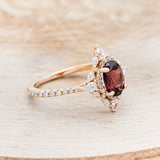 Shown here is "North Star", an oval garnet women's engagement ring with a diamond halo and accents, facing right. Many other center stone options are available upon request.