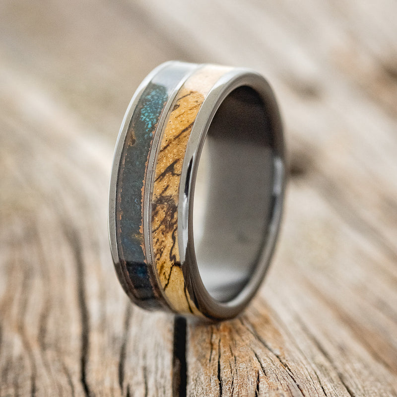 Shown here is "Dyad", a custom, handcrafted men's wedding ring featuring 2 channels with spalted maple wood and patina copper inlays, upright facing left.