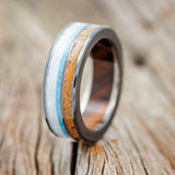 Shown here is "Element", a custom, handcrafted men's wedding ring featuring orange opal, elk antler, and turquoise inlays on an ironwood lined band, upright facing left.