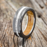 Shown here is "Nirvana", a custom, handcrafted men's wedding ring featuring authentic whiskey barrel oak lining and an elk antler inlay, upright facing left.