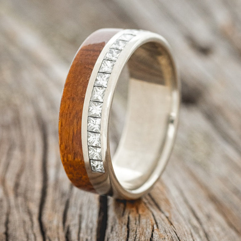 Shown here is a custom, handcrafted men's wedding ring featuring a koa wood overlay and a channel with 8 princess cut diamonds, upright facing left. Additional material options are available upon request.