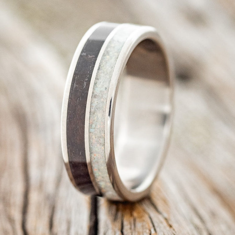 Shown here is "Dyad", a custom, handcrafted men's wedding ring featuring 2 channels with fire and ice opal and jet stone inlays, upright facing left. Additional inlay options are available upon request.