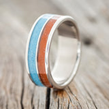 Shown here is "Dyad", a custom, handcrafted men's wedding ring featuring 2 channels with red jasper & turquoise inlays, upright facing left. Additional inlay options are available upon request.