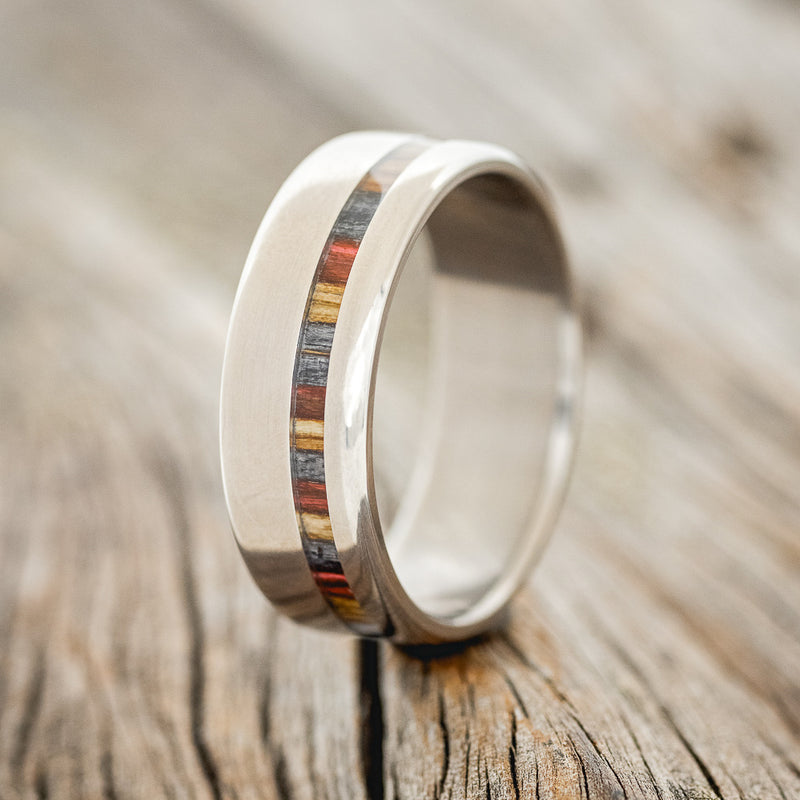 Shown here is "Vertigo", a handcrafted men's wedding ring featuring an offset inlay with red, grey and brown birch wood, upright facing left. 