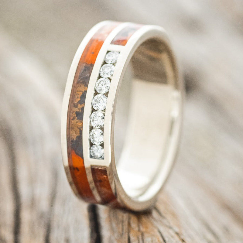 Shown here is "Trident", a custom, handcrafted men's wedding ring featuring a 14K gold band with 7 round cut diamonds set into the ring with red patina copper inlays, upright facing left. Additional inlay options are available upon request.