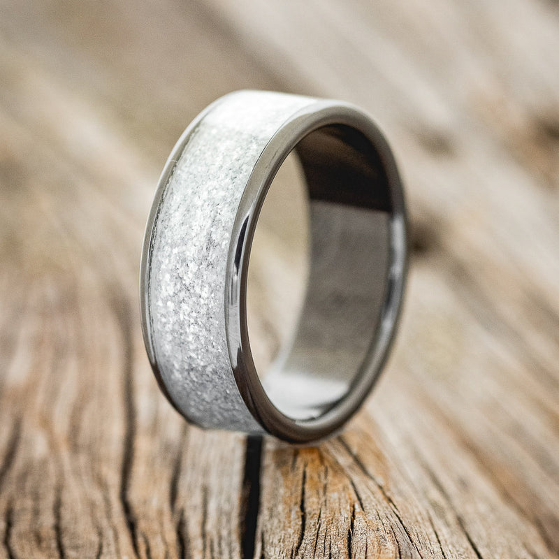 Shown here is "Rainier", a custom, handcrafted men's wedding ring featuring a diamond dust inlay on a fire-treated black zirconium band, upright facing left. Additional inlay options are available upon request.