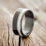 Shown here is "Raptor", a custom, handcrafted men's wedding ring featuring African black wood and naturally shed elk antler inlays, upright facing left.
