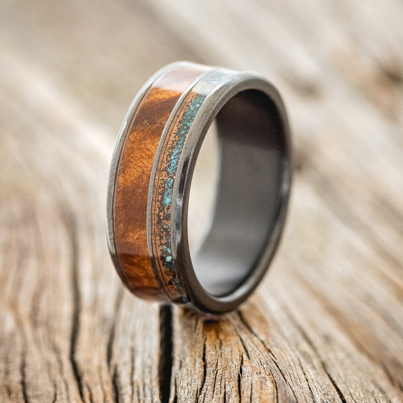 Shown here is "Raptor", a custom, handcrafted men's wedding ring featuring a patina copper and redwood inlays on a fire-treated black zirconium band, upright facing left. Additional inlay options are available upon request.
