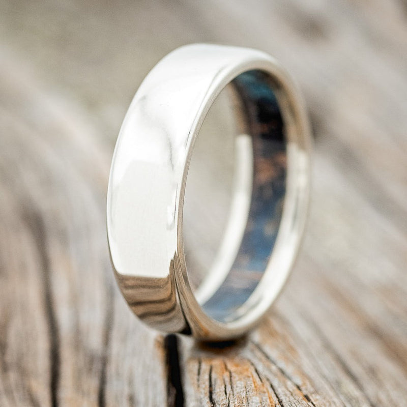 Shown here is a handcrafted men's wedding ring featuring a patina copper lined band, upright facing left. Additional lining options are available upon request.