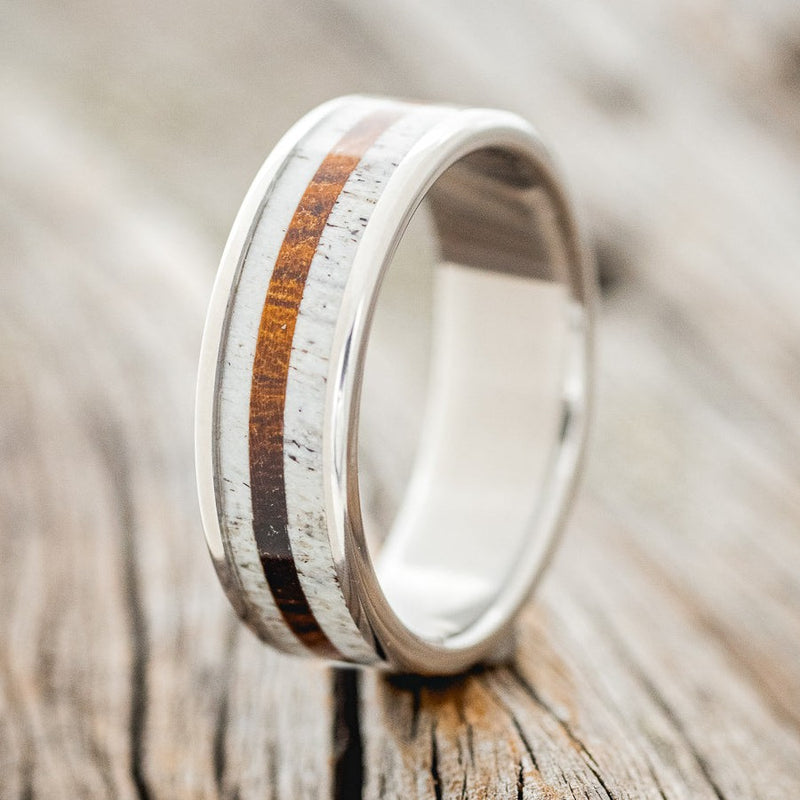 Shown here is "Rainier", a custom, handcrafted men's wedding ring featuring antler and ironwood inlays on a titanium band, upright facing left. Additional inlay options are available upon request.